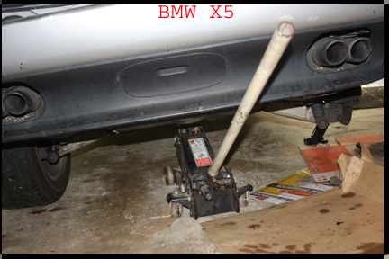 BMW X5 - Shows floor jack under rear end as safety measure when jacking up rear of X5 for rotor replacement.
